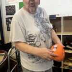 An Excited bill carpenter rearranging his Halloween display.(holding pumpkin)